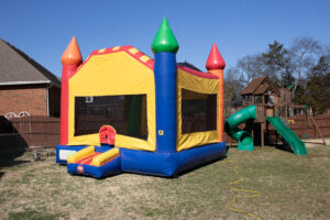 Children playing in colorful inflatable bounce house during outdoor birthday party celebration