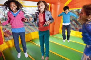 Children playing in colorful inflatable bounce house during outdoor birthday party celebration